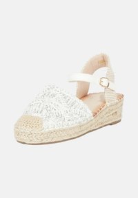 Sandalo con zeppa espadrille bianco, caratterizzato da una tomaia in tessuto intrecciato con accenti argentati, un sottopiede in juta intrecciata e una fascia alla caviglia con una fibbia dorata.