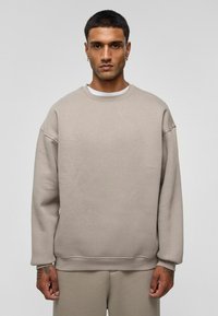 Beige sweatshirt met een ronde hals, verlaagde schouders en geribbelde boorden. Gemaakt van zachte stof, met een eenvoudig, minimalistisch ontwerp.