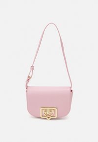 Růžová kožená crossbody taška se zlatým zapínáním. Má hladký povrch, zakřivený tvar a nastavitelný popruh.