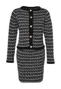 Tailleur jupe en tweed noir et blanc avec manches longues, boutons dorés sur le devant, et une jupe crayon ajustée.