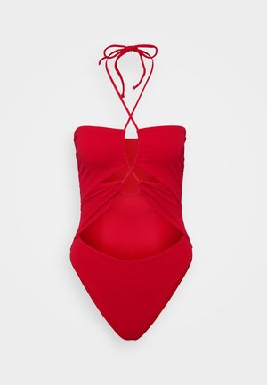 Maiô vermelho de uma peça com tecido texturizado, design sem alças, detalhes recortados nas laterais e fechos finos de laço no pescoço.