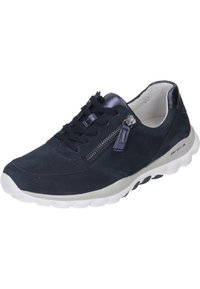 Marineblauwe suède sneaker met vetersluiting aan de voorkant, zijrits, witte gepolsterde zool en textuuraccenten langs het bovenwerk.