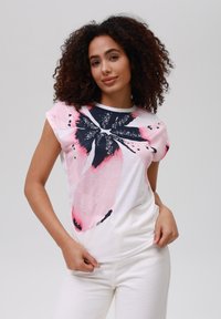 Hvit t-skjorte med kort erm som har et stort blomsterdesign i rosa og marineblå. Stoffet er glatt, med rund hals og avslappet passform.