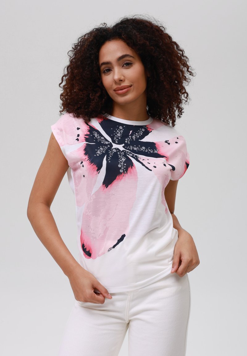 Hvit t-skjorte med kort erm som har et stort blomsterdesign i rosa og marineblå. Stoffet er glatt, med rund hals og avslappet passform.