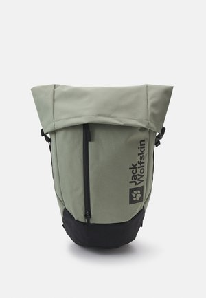 Zaino verde chiaro con fondo nero, dotato di un coperchio superiore, tasca frontale con zip e logo "Jack Wolfskin". Tessuto testurizzato e resistente.