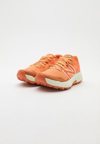 Scarpe da ginnastica arancioni con una tomaia texturizzata, lacci e un logo 'N' bianco. Presentano una soletta ammortizzata e un battistrada robusto per una buona aderenza.