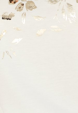 Tissu blanc parsemé de sequins dorés et de broderies métalliques formant des formes florales abstraites près du haut.