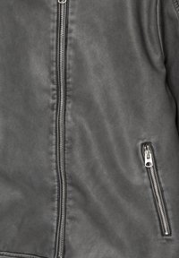 Giacca di pelle grigia scura con zip centrale in argento e una piccola tasca con zip angolata sul lato destro.