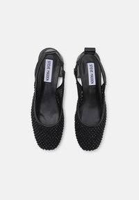 Black slingback shoes with pointed toes, featuring a textured surface adorned with small studs, and a smooth leather heel strap.