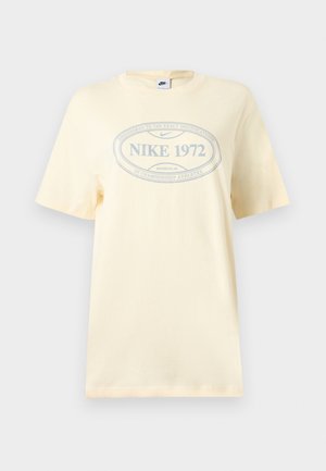 Μπεζ κοντομάνικη μπλούζα Nike με στρογγυλή λαιμόκοψη και οβάλ λογότυπο "NIKE 1972" σε ανοιχτό γκρι στο μπροστινό μέρος.