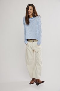 Ανοιχτό γαλάζιο πλεκτό πουλόβερ με χαλαρή εφαρμογή, μπεζ παντελόνι με φαρδιά πόδια και καφέ μποτάκια αστραγάλου με τετράγωνο τακούνι. Φυσική υφή και καθημερινός σχεδιασμός.