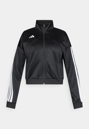 Black cropped jacket made of smooth material, featuring a high collar, zip closure, and white side stripes on the sleeves. Logo on left shoulder.