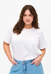 T-shirt bianco in cotone con maniche corte, scollatura rotonda e texture a coste, abbinato a jeans in denim blu a vita alta. Design semplice e classico.
