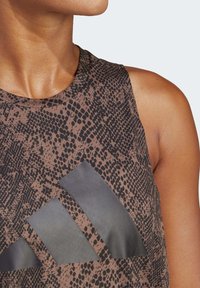 Top atlético sin mangas de color marrón con un patrón de piel de serpiente y acentos del logotipo negro de Adidas. Tejido suave con una textura lisa, que enfatiza la comodidad.