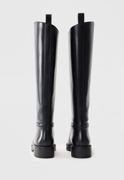 Botas de cuir negras por encima de la rodilla con una textura suave, diseño minimalista y un tacón cuadrado, con tiradores en la parte superior y costuras laterales.