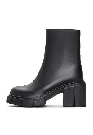 Botines negros de tobillo hechos de material sintético liso con un tacón robusto y suela estriada. El diseño es elegante con una silueta minimalista.