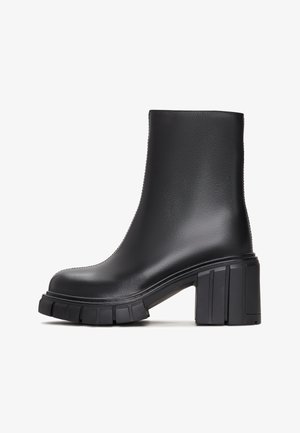 Schwarze Knöchelstiefel aus glattem synthetischen Material mit klobigem Blockabsatz und gerippter Sohle. Das Design ist elegant mit einer minimalistischen Silhouette.