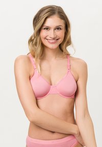 Rosa gepolsterter BH mit verstellbaren Trägern, nahtlosem Design und runden Cups. Die weiche Textur und die dezenten Nähdetails heben sein Aussehen hervor.