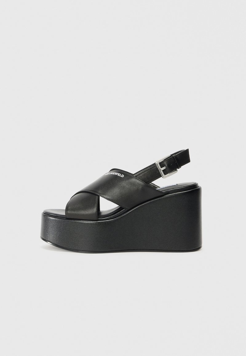 Sandali con piattaforma nera, dal design a fascia incrociata ampia e fibbia regolabile alla caviglia. Finitura in pelle liscia e suola a zeppa spessa.