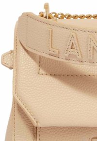 Sac à main en cuir beige avec une surface texturée, une bandoulière en chaîne dorée, un lettrage embossé "LAN" sur le rabat, et des éléments de design angulaires.