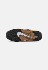 Shoe sole features a multi-directional tread with black and gum rubber, a central white Nike swoosh, and a textured pattern for traction.