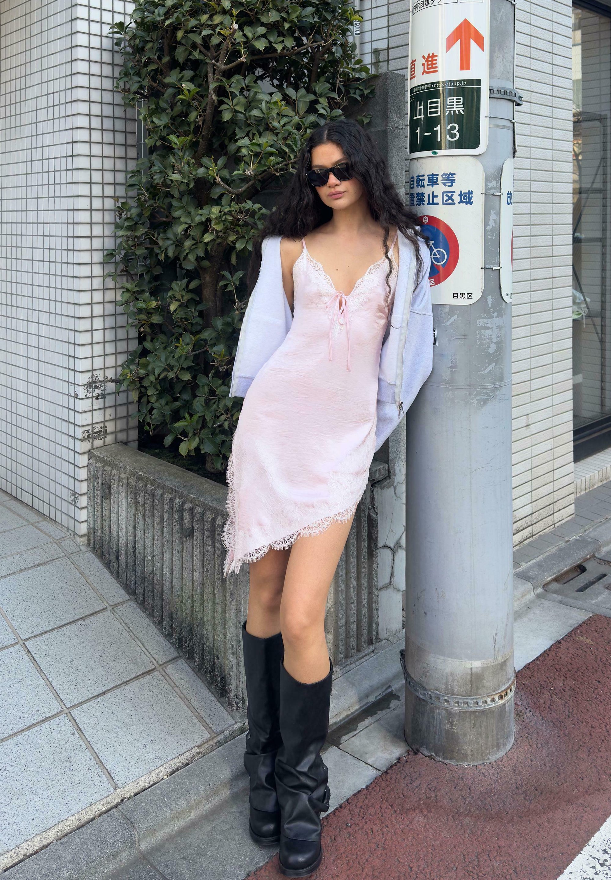 light pink dress with black boots Young fashionable girl in pink dress and high black leather boots standing  and posing against grey