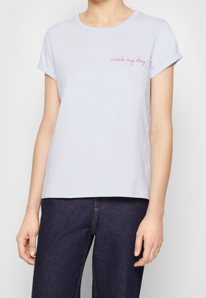 Personne portant un t-shirt à manches courtes bleu clair avec le texte rouge « made my day » sur la poitrine et un jean bleu foncé.