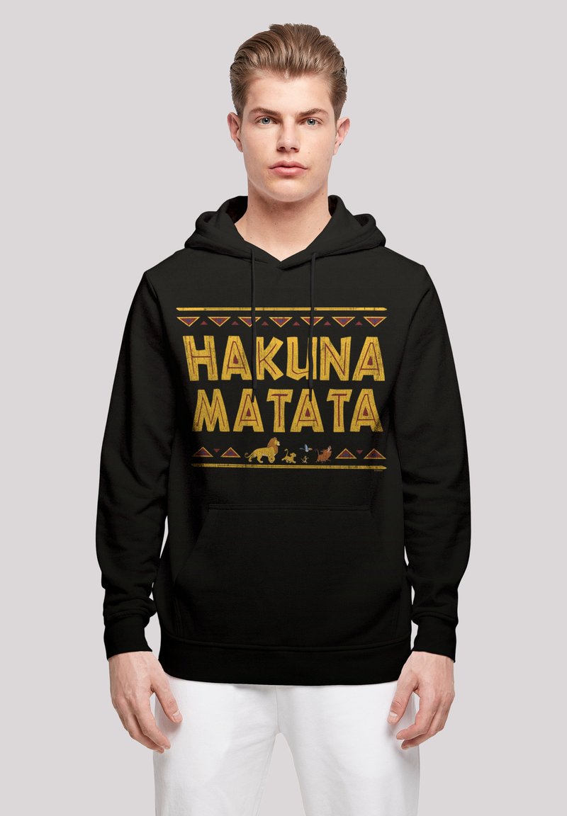 Svart hoodie med texten "HAKUNA MATATA" i fet gul färg, accentuerad med djursilhuetter och geometriska mönster i röd färg.