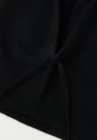 Sort strikket sweater med en blød tekstur, ribbet kant og let samling ved halsudskæringen. Enkel, alsidig design der er velegnet til lag-på-lag.