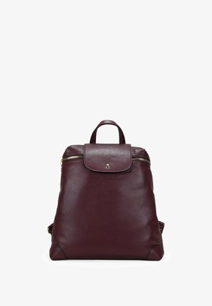 Mochila de cuero granate con forma redondeada, asa superior, cierre de cremallera y detalles en metal dorado, con una superficie texturizada.