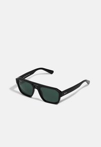 Melni taisnstūra saulesbrilles ar zaļiem stikliem. Izgatavotas no plastmasas ar oktagonālu formu un gludu apdari. Sānos redzama Ray-Ban zīmola nosaukums.