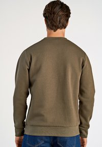 Felpa verde oliva realizzata in tessuto textures, con un classico collo a giro e polsini e orlo a costine.