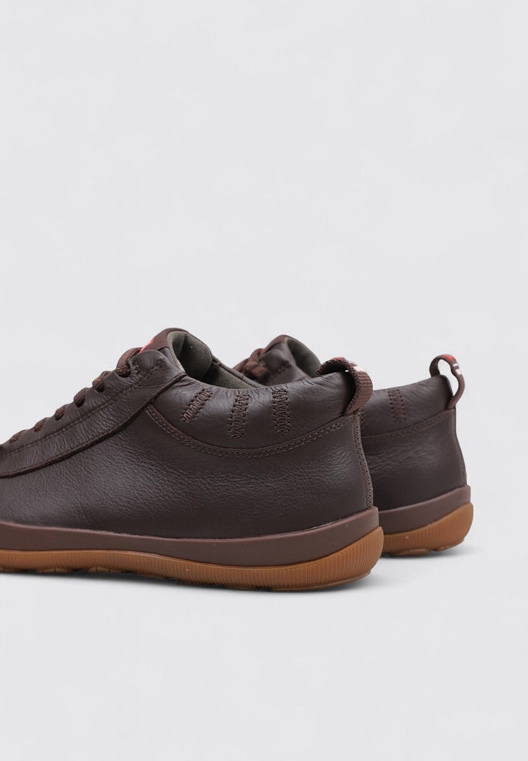 Brune lædersneakers med rund tå, struktureret overflade, flade snørebånd og diskret syning. Gummisål med en kontrasterende brun træd.