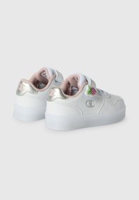 Sneakers bianchi con accenti metallici, pannelli testurizzati e un rivestimento rosa. Presentano una patch a forma di fragola e una chiusura con cinturino sicura.
