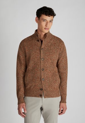 Braun und orange strukturierter Strickcardigan mit hohem Kragen, fünf Knöpfen und gerippten Bündchen. Getragen über einem dunklen Hemd und hellen Hosen.