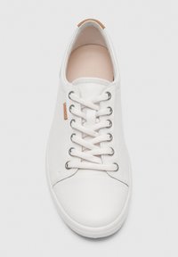 Biały niski skórzany sneaker z białymi sznurowadłami, metalowymi oczkami i małą beżową tkaną metką z boku.