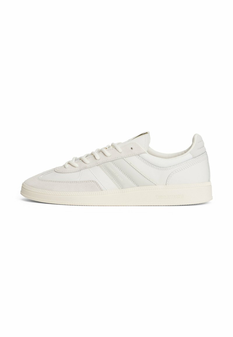 Zapatilla blanca de cuero con acentos de ante, suela de goma, cordones planos y tres elementos de diseño a rayas en el lateral. Estructura minimalista y clásica.