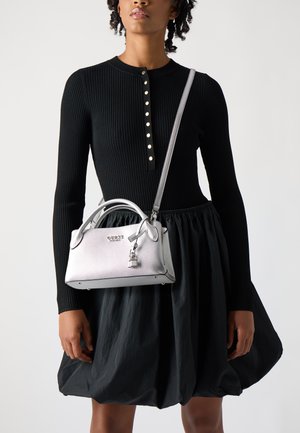 Borsa argentata con design strutturato e finitura testurizzata. Presenta una maniglia superiore, una tracolla removibile e un piccolo dettaglio a forma di lucchetto. Abito nero a costine.