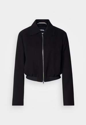 Veste courte noire avec une fermeture éclair à l'avant, col classique, manches longues et ourlet côtelé. Fabriquée dans un matériau lisse sans motifs visibles.