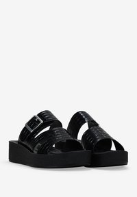 Sandal negra con patrón de falso cocodrilo brillante, dos correas anchas, acento de hebilla plateada y una suela gruesa de espuma negra.