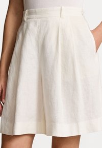 Lněné šortky v barvě slonové kosti, s vysokým pasem, sklady, bočními kapsami a čistým lemem pro elegantní vzhled.