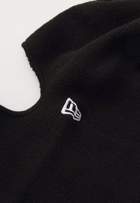 Schwarzer Strickstoff mit einer enganliegenden Passform und einem runden Halsausschnitt. Verfügt über ein kleines, weiß gesticktes Logo auf der Vorderseite.
