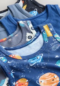 Pile de débardeurs pour enfants bleus et gris, certains avec des imprimés colorés sur le thème des planètes et de l'espace, incluant Mars et Jupiter.