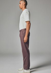 Mænds grå kortærmet skjorte kombineret med dyb maroon bukser. Bukserne har slim fit, sidelommer og bæres med hvide sneakers.