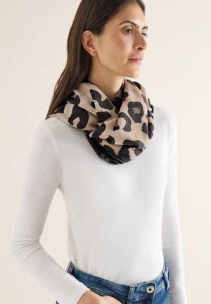 Sciarpa stampata leopardata in beige e nero, texture morbida, avvolta intorno al collo, abbinata a una camicia bianca a maniche lunghe e jeans di denim.