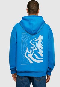 Blå hættejakke med snoretræk i hætten, med et stort hvidt grafisk design på ryggen. Blødt materiale, oversized pasform, ribbede manchetter.