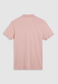 Polo shirt rose clair à manches courtes avec un col classique et une texture douce et lisse. Design simple sans motifs ni accents visibles.