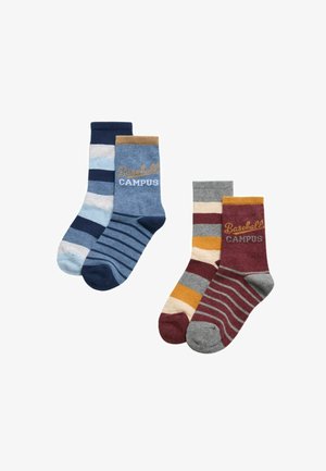 Conjunto de cuatro calcetines con diferentes patrones de rayas. Los colores incluyen azul, azul marino, gris, granate, amarillo y crema. En algunos calcetines aparece el texto "Baseball CAMPUS".