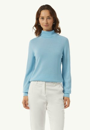 Light blue turtleneck sweater in soft, fine knit fabric with long sleeves. Features ribbed cuffs and a relaxed fit. Paired with white trousers.