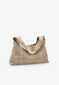 Bolso tote de ante beige suave, con un diseño de parte superior abierta, asas curvadas y costuras mínimas. La textura es lisa con un acabado mate.